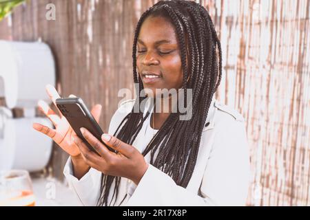 Eine afroamerikanische Frau, die ihr Smartphone im Freien benutzt Stockfoto