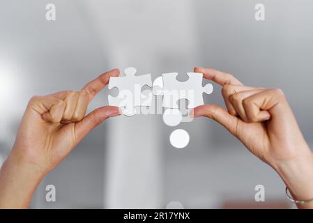 Alle Teile kommen zusammen. Eine unbekannte Geschäftsfrau, die zwei Puzzleteile hochhält. Stockfoto