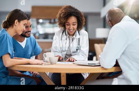 Ungezwungenes Treffen beim Mittagessen. Eine Gruppe junger Ärzte, die sich tagsüber bei einem Kaffee an einem Tisch in einem Krankenhaus treffen. Stockfoto