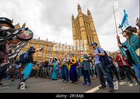 LONDON - 22. April 2023: Ausrottung Rebellion Demonstranten marschieren vorbei an den berühmten Houses of Parliament in London, vereint in ihrem Ruf nach sozialem und Stockfoto