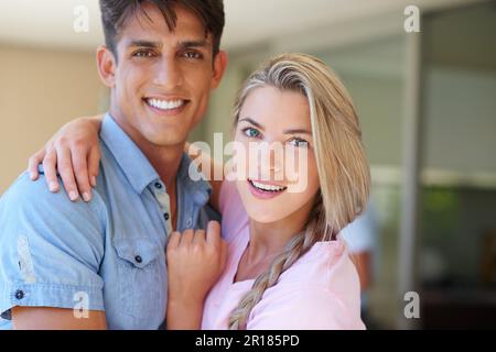 Jung und verliebt. Porträt einer wunderschönen jungen Frau, die mit dem Arm um ihren Freund steht. Stockfoto