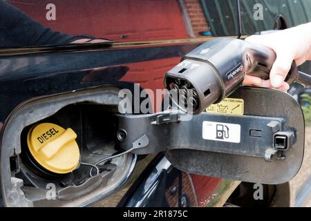 Anschluss für ein Ladegerät für Elektrofahrzeuge neben dem Tankdeckel für Dieselkraftstoff eines Fahrzeugs, das mit fossilem Kraftstoff betrieben wird. Stockfoto