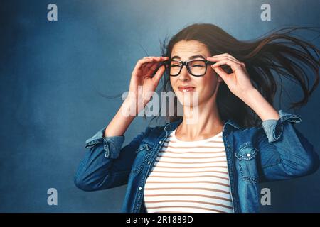 Wenn sie die Musik auf volle Kraft stellen. Studiofoto einer jungen Frau, die vor blauem Hintergrund Luft ins Gesicht geblasen hat. Stockfoto