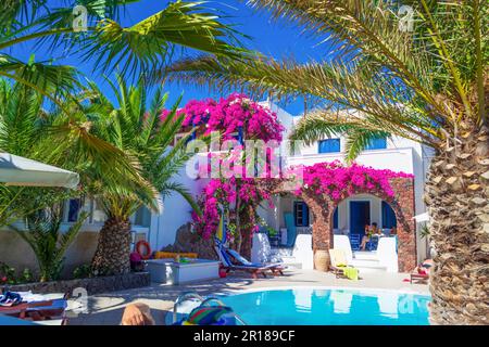 Malerische Terrasse mit blühender rosafarbener Bougainvillea Pflanze, tiefblauem Himmel und gewölbten Dächern - Kamari Dorf Santorini Insel, Griechenland Stockfoto