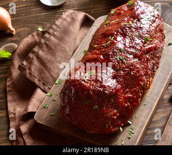 Hackbraten mit Glasur auf Schneidebrett auf Holzhintergrund. Nahaufnahme Stockfoto