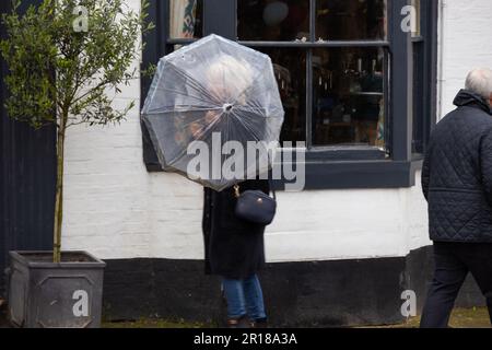 Tenterden, Kent, Großbritannien. 12. Mai 2023. Wetter im Vereinigten Königreich: Die Menschen schützen sich am meisten vor Regen mit Regenschirmen in der High Street von Tenterden, Kent, Großbritannien. Fotograf: Paul Lawrenson, Fotograf: PAL News/Alamy Live News Stockfoto