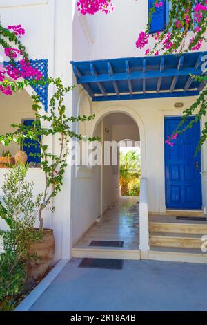 Malerische Terrasse mit blühender rosafarbener Bougainvillea-Pflanze, tiefblauem Himmel und gewölbten Dächern - typischer Blick von der Ostküste von Santorin, Griechenland Stockfoto