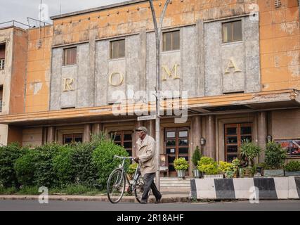 Asmara, Eritrea. 8. Mai 2023. Ein älterer schiebt sein Fahrrad vor das Wahrzeichen des Cinema Roma in Asmara, Eritrea, am 8. Mai 2023. Das Radfahren wurde in das Leben der Einheimischen integriert und wurde zu einem wichtigen Sport in Eritrea. Kredit: Wang Guansen/Xinhua/Alamy Live News Stockfoto