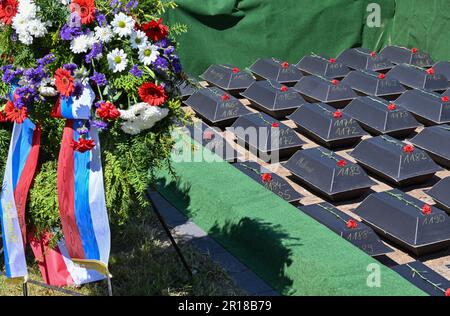 Lebus, Deutschland. 12. Mai 2023. Ein Kranz der russischen Botschaft ist neben einem Grab mit kleinen Särgen der Überreste von Soldaten der Roten Armee am Grab des Sowjetkriegs zu sehen. 78 Jahre nach dem Ende des Zweiten Weltkriegs hatte die Kommission der Kriegsgräber 61 Soldaten der Roten Armee in Lebus (Bezirk Märkisch-Oderland) zur Ruhe gesetzt. Sie starben in den Schlachten in Oderbruch und in der Schlacht um Berlin und wurden in den letzten Monaten von der Kommission der Kriegsgräber wieder gefunden. Kredit: Patrick Pleul/dpa/Alamy Live News Stockfoto