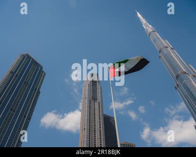 Flagge der Vereinigten Arabischen Emirate, die gegen die Skyline von Dubai in der Innenstadt weht. Die Vereinigten Arabischen Emirate feiern jedes Jahr am 2. Dezember den Nationalfeiertag. Stockfoto