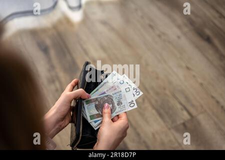 Frau, die polnische złoty-Banknoten prüft. Sie scheint fokussiert und aufmerksam zu sein und weist darauf hin, wie wichtig es ist, in finanziellen Fragen wachsam zu sein Stockfoto
