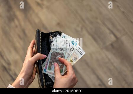Frau, die polnische złoty-Banknoten prüft. Sie scheint fokussiert und aufmerksam zu sein und weist darauf hin, wie wichtig es ist, in finanziellen Fragen wachsam zu sein Stockfoto