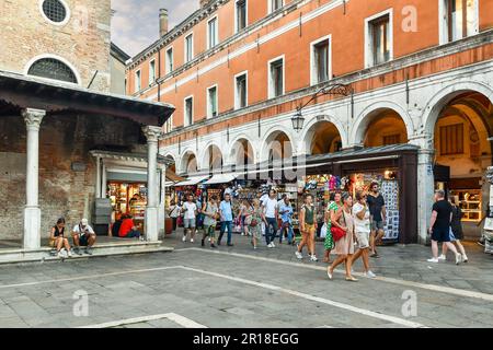 Touristen, die in der Ruga dei Oci Straße neben der Rialtobrücke mit der Kirche San Giacomo von Rialto in der Sestiere von San Polo, Venedig Italien, spazieren gehen Stockfoto