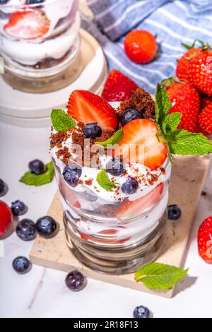 Erdbeerdessert mit Parfait in verschiedenen Schichten mit Schokoladenschwamm, Schlagsahne und frischen Beeren. Sommerfrühstück mit Nachtisch in Glas Stockfoto