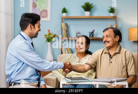 Indischer Bankangestellter grüßt Seniorenpaar zu Hause durch Handschütteln - Konzept von Finanzberater, Expertenberatung und Profi Stockfoto