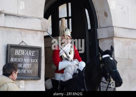 Whitehall, London, Großbritannien. 28. April 2023. Ein King's Life Guard setzte zwei montierte Wachen auf der Horse Guard's Parade in Whitehall ein. Trotz klarer Schilder, die Besucher und Touristen darauf hinweisen, dass die Pferde treten oder beißen können, bestehen Touristen immer noch darauf, direkt neben den Pferden zu stehen und zu bewachen. Es gab in letzter Zeit mehrere Male, dass ein Wachmann einen Touristen rufen musste, um zurückzukommen. Kredit: Maureen McLean/Alamy Stockfoto