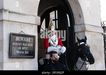 Whitehall, London, Großbritannien. 28. April 2023. Ein King's Life Guard setzte zwei montierte Wachen auf der Horse Guard's Parade in Whitehall ein. Trotz klarer Schilder, die Besucher und Touristen darauf hinweisen, dass die Pferde treten oder beißen können, bestehen Touristen immer noch darauf, direkt neben den Pferden zu stehen und zu bewachen. Es gab in letzter Zeit mehrere Male, dass ein Wachmann einen Touristen rufen musste, um zurückzukommen. Kredit: Maureen McLean/Alamy Stockfoto