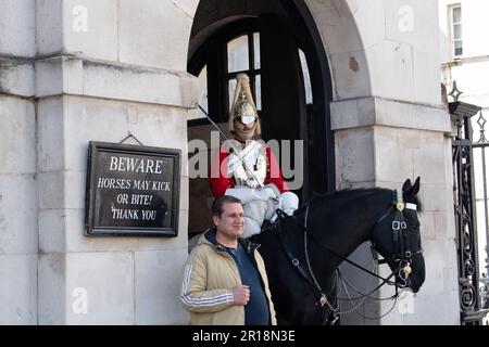 Whitehall, London, Großbritannien. 28. April 2023. Ein King's Life Guard setzte zwei montierte Wachen auf der Horse Guard's Parade in Whitehall ein. Trotz klarer Schilder, die Besucher und Touristen darauf hinweisen, dass die Pferde treten oder beißen können, bestehen Touristen immer noch darauf, direkt neben den Pferden zu stehen und zu bewachen. Es gab in letzter Zeit mehrere Male, dass ein Wachmann einen Touristen rufen musste, um zurückzukommen. Kredit: Maureen McLean/Alamy Stockfoto