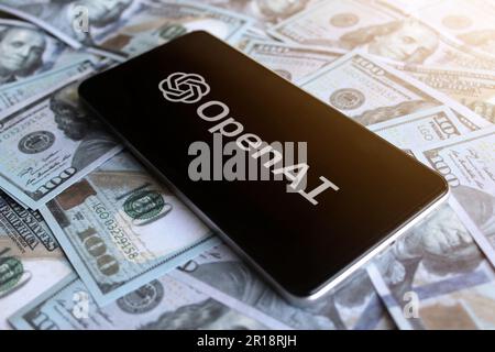OpenAI-Logo auf dem Smartphone auf dem Geldhaufen. Stockfoto