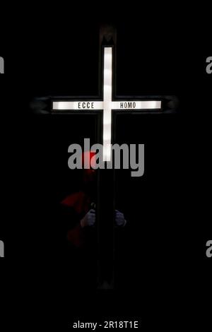 Ein Mitglied des Hermandad del Santo Cristo de los Artilleros trägt während einer Semana Santa Prozession in Valladolid, Spanien, ein beleuchtetes Kreuz Stockfoto