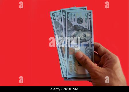 Nahaufnahme einer Hand mit US-Dollar-Geldern auf rotem Hintergrund und Kopierbereich Stockfoto