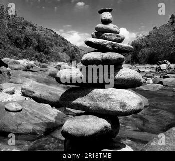 Steinhaufen in einem Seehintergrund. Nahaufnahme einer Steinwaage. Schwarz und Weiß Stockfoto