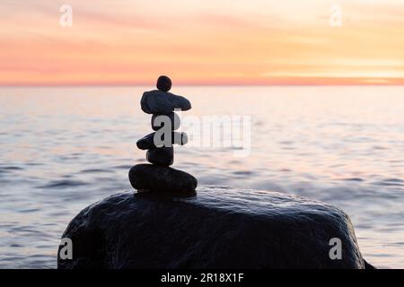 Steinpyramiden am traumhaften Ostsee-Sandstrand auf Rügen zum spektakulären Sonnenuntergang in Orange Stockfoto