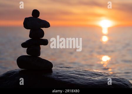 Steinpyramiden am traumhaften Ostsee-Sandstrand auf Rügen zum spektakulären Sonnenuntergang in Orange Stockfoto