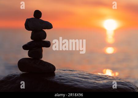 Steinpyramiden am traumhaften Ostsee-Sandstrand auf Rügen zum spektakulären Sonnenuntergang in Orange Stockfoto