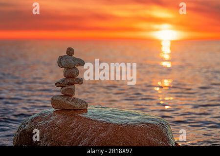 Steinpyramiden am traumhaften Ostsee-Sandstrand auf Rügen zum spektakulären Sonnenuntergang in Orange Stockfoto