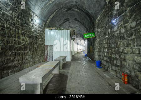 CHONGQING, CHINA - 8. MAI 2023 - das am 8. Mai 2023 aufgenommene Video zeigt einen Lebensmittelmarkt in einem verlassenen Eisenbahntunnel in Chongqing, China. In diesem hundert Meter langen Tunnel sind mehr als 20 Stände nacheinander angeordnet. Die Verkaufsstände sind in feste Verkaufsstände und provisorische Verkaufsstände unterteilt, und die festen Verkaufsstände sind in Fleischbereiche und Bereiche für Wasserprodukte unterteilt. Es wird davon ausgegangen, dass der Tunnel Teil der ehemaligen Eisenbahnlinie des Spezialstahlwerks Chongqing ist, die eine Tunnellänge von etwa 150 Metern hat. Nach dem Bankrott des Spezialstahlwerks Chongqing wurden die einst befahrenen Tunnel allmählich still, A Stockfoto