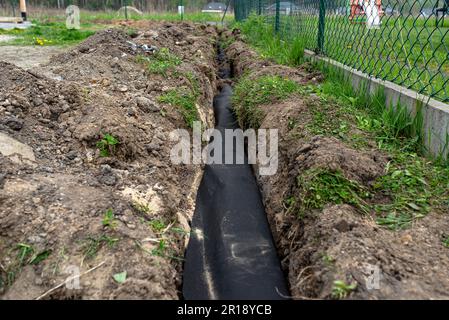 Abflussrohr in Geotextil eingewickelt, in einen Graben im Haus eingesteckt. Stockfoto