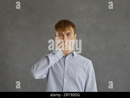 Studioporträt-Porträt eines jungen rothaarigen Mannes, der den Mund mit der Handfläche verdeckt Stockfoto
