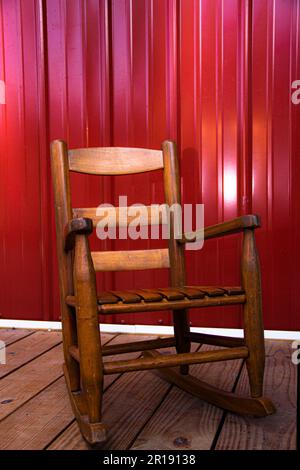 Kinderschaukelstuhl aus Holz auf der Veranda mit Metallverkleidung Stockfoto