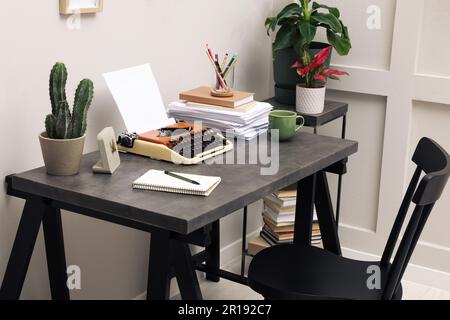 Schreibmaschine und Papierstapel auf dunklem Tisch im Zimmer. Schreibarbeitsplatz Stockfoto