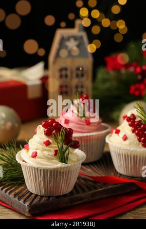 Köstliche Cupcakes und Weihnachtsdekorationen auf einem Holztisch Stockfoto