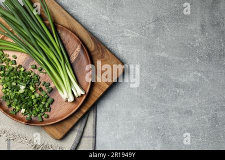 Gehackte grüne Frühlingszwiebel und Stiele auf grauem Tisch, Draufsicht. Platz für Text Stockfoto