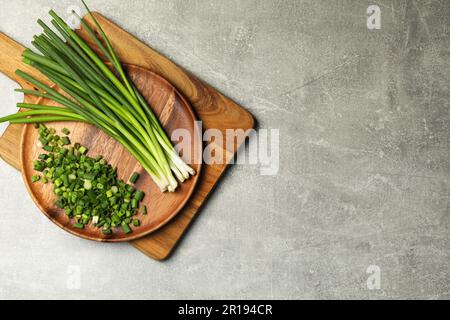 Gehackte grüne Frühlingszwiebel und Stiele auf grauem Tisch, Draufsicht. Platz für Text Stockfoto