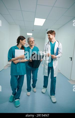 Eine Gruppe glücklicher Ärzte geht den Krankenhausflur entlang Stockfoto