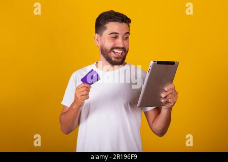 Brasilianischer lateinamerikanischer Mann, überrascht und glücklich, Tablet und Kreditkarte in Besitz, Einkäufe über App oder Internet. Stockfoto