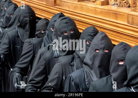 Mitglieder des Cofradía del Cristo del Gran Poder tragen während einer Semana-Santa-Prozession in Leon, Spanien, einen Paso Stockfoto