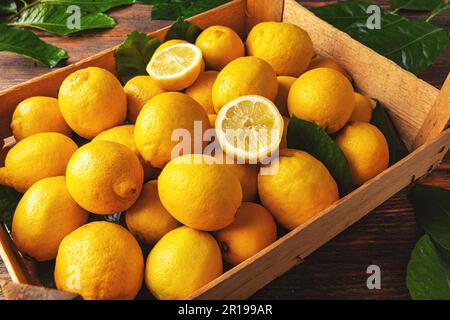 Frische Zitrone mit Blättern in der Kiste, Nahaufnahme Stockfoto