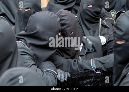 Mitglieder des Cofradía del Cristo del Gran Poder unterhalten sich während einer Semana-Santa-Prozession in Leon, Spanien Stockfoto