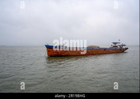 Ein rostiges altes Frachtschiff, das auf See in der Bai TU Long Bay, Halong Bay, Vietnam, vor Anker ging. Stockfoto