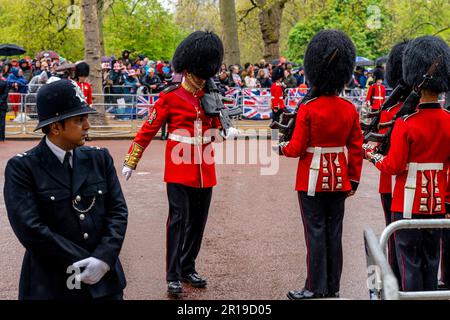 Ein Wächter inspiziert die Uniform Einer Fellow Guard vor der Königlichen Prozession, der Krönung von König Karl III., London, Großbritannien. Stockfoto