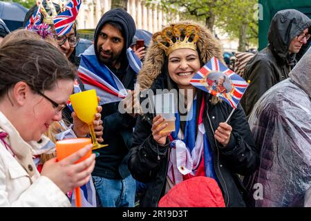 Junge Briten, die auf der Mall stehen, stoßen auf den Neuen König an, die Krönung von König Karl III., London, Großbritannien. Stockfoto