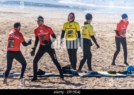 Leute, die sich während einer Surfstunde am Fistral Beach in Newquay in Cornwall in Großbritannien aufwärmen. Stockfoto