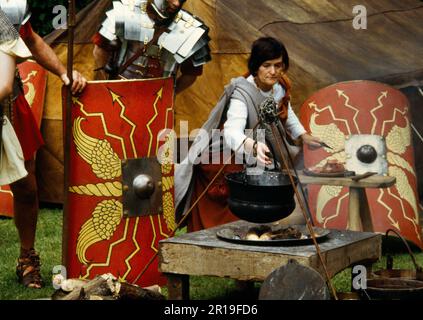 Zubereitung und Kochen von Fleisch in einem Kessel über einem Holzfeuer während einer Ausstellung der Ermine Street Guard im Loggerheads Country Park, North Wales, Großbritannien. Stockfoto