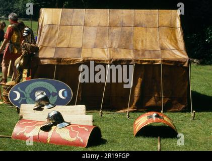 Nachbildungen römischer Schutzschilde, Helme und Ziegenhaut-Zelt bei einer Ausstellung der Ermine Street Guard im Loggerheads Country Park, Denbighshire, Wales, Großbritannien. Stockfoto