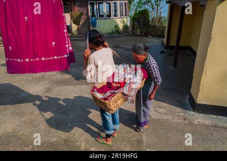 Sikkim, Indianer - 22. März 2004 : Sikkimesische Mutter, die ihr Baby auf dem Rücken trägt. Großmutter beobachtet das Baby. Mütter in Sikkim arbeiten sehr hart. Stockfoto